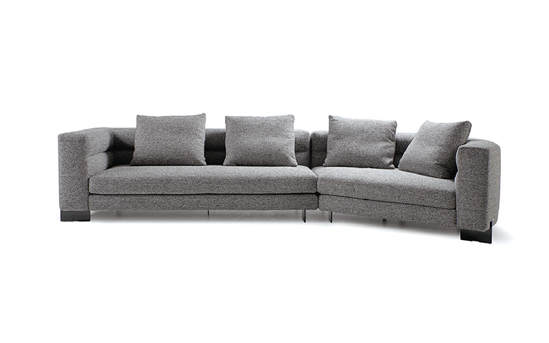 A large, modern L-shaped sectional sofa with gray textured upholstery and four matching back cushions against a white background.