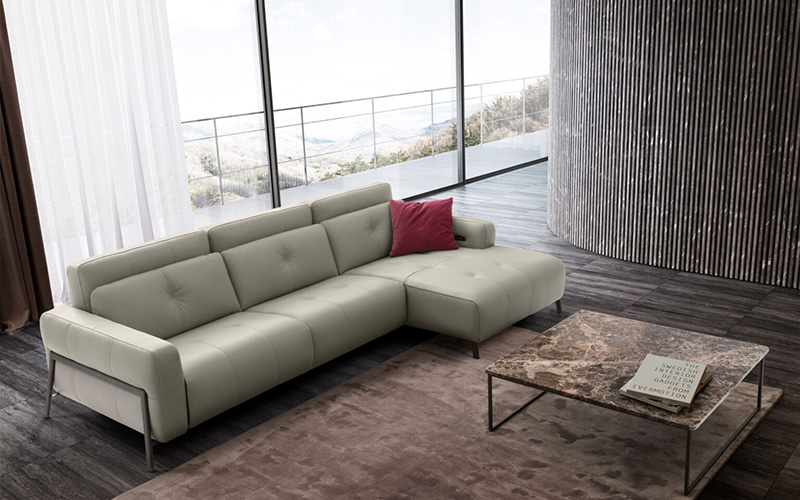 Minimalist living room with light gray sectional sofa, marble coffee table, and mountain view through large windows.
