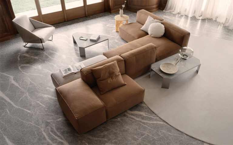 Modern living room with brown sectional sofa, glass-top coffee tables, and large windows with sheer curtains.