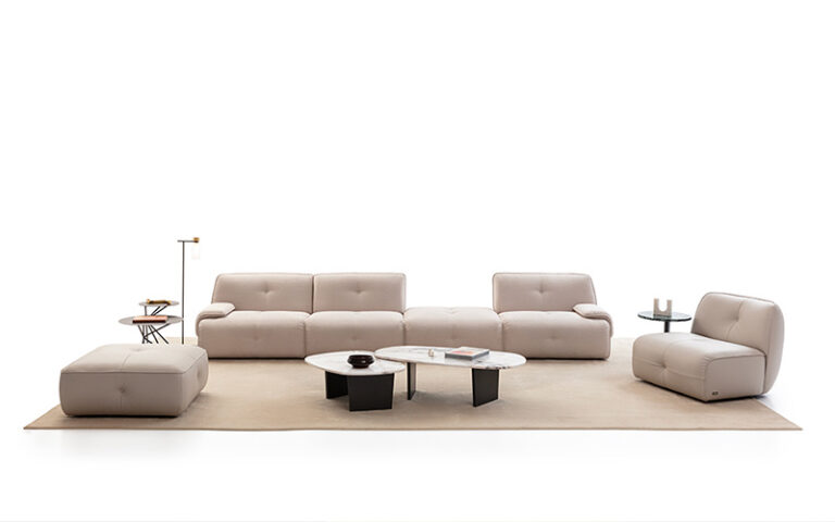 A modern living room arrangement featuring a modular sofa and matching ottoman on a neutral rug.