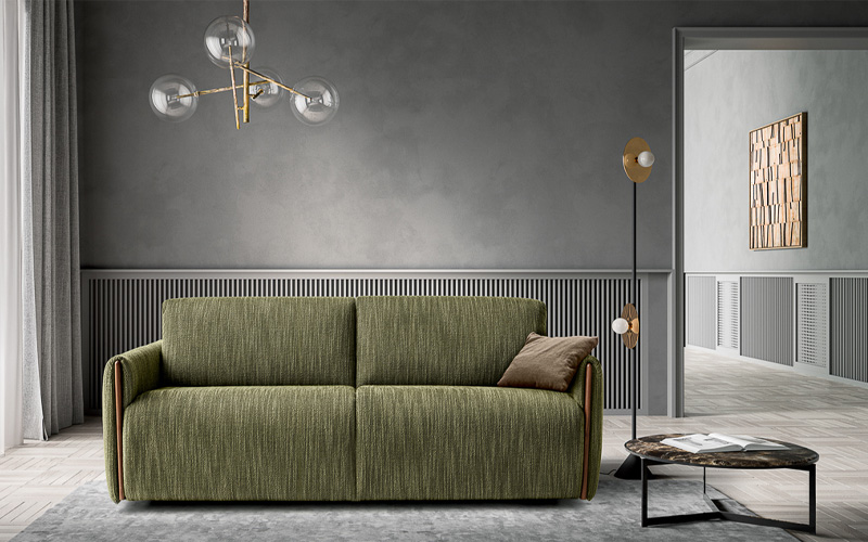 Minimalist living room with green sofa, marble coffee table, gold chandelier, and gray paneled walls.