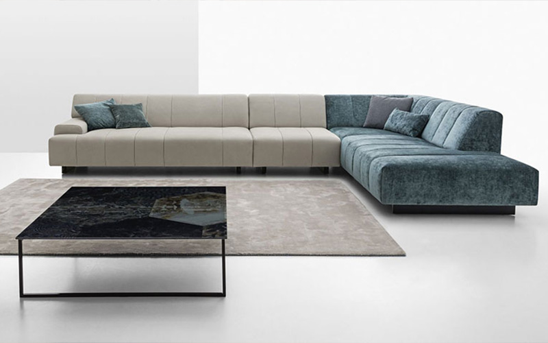 Designer living space showcasing an L-shaped sectional sofa with mixed upholstery and textures.