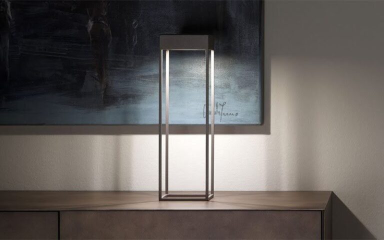 A sleek, rectangular modern table lamp casting a soft glow against a wall with abstract art.