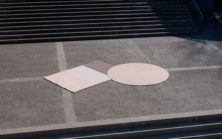 Rectangular and round Colzani outdoor rugs on a stone terrace.