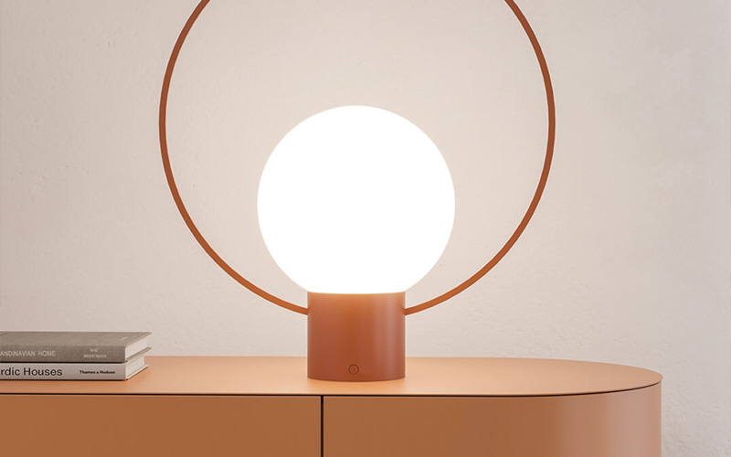 A contemporary spherical table lamp with a sleek copper base
